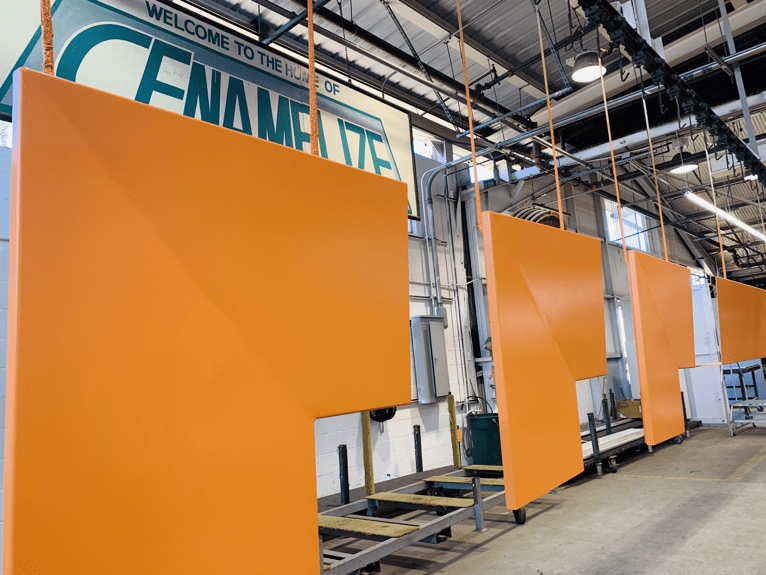 Orange panels hanging under a sign that says, "Welcome to the home of Cenamelize"